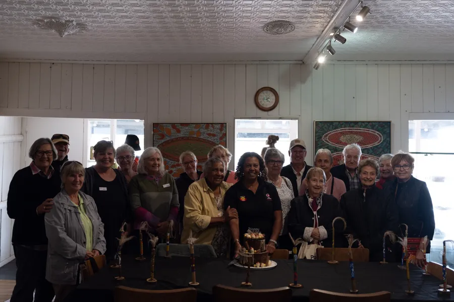 A workshop group poses together holding their finished message sticks.